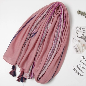 Close-up of pink ethnic scarf with blue wave patterns and fringe tassels detail