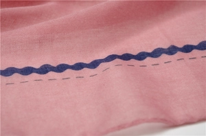 Detail of soft pink shawl fabric featuring blue wave patterns and delicate textures