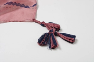 Detail of pink ethnic shawl featuring blue wave prints and two-tone tassel edges