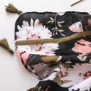 Close-up of bohemian floral beach shawl with green tassels and soft linen texture
