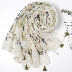 Vue détaillée d'une écharpe en coton et lin à fleurs avec franges et motifs végétaux colorés