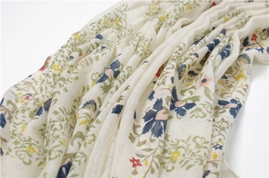 Détail macro d'une écharpe en coton et lin avec imprimés floraux colorés et des franges