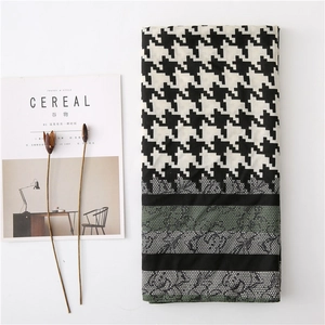 Detail of houndstooth scarf with dark green lace patchwork and dried floral decor