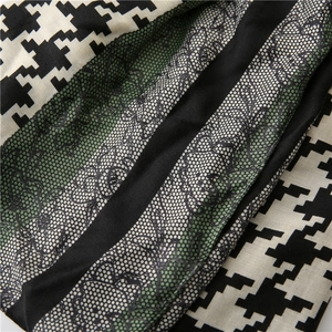 Macro shot of houndstooth pattern and delicate black floral lace stitching on scarf fabric
