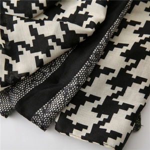Close-up of houndstooth scarf featuring delicate black floral lace stitching and soft fabric