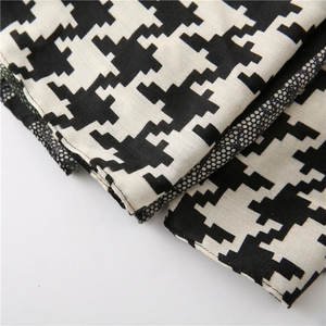 Detailed view of houndstooth scarf fabric with delicate black lace trim and stitching