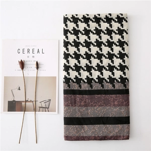 Detail of long houndstooth scarf featuring black and white patterns with lace print border