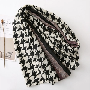 Detail of houndstooth scarf with purple floral lace trim on minimalist white background