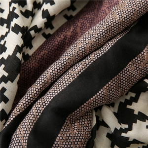 Detailed view of scarf featuring houndstooth, red stripes, and interlocking patterns