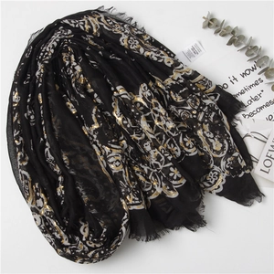 Elegant black polyester scarf with gold foil paisley print and fringe detail in flat lay