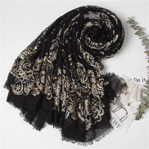 Elegant black shawl with gold floral print and fringe details on a white background