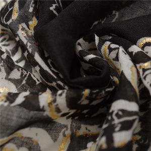 Macro shot of paisley pattern on thin scarf with shimmering gold foil details