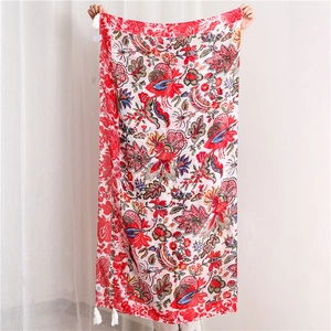 Detail of red floral bali yarn shawl with white tassel fringe and tropical flower patterns