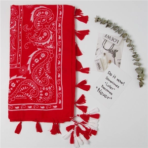 Détail d'un châle en coton rouge avec motif paisley et finitions à franges