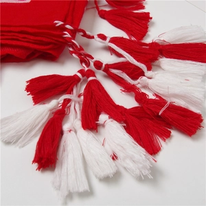 Détail des longs pompons rouges et blancs d'une écharpe en coton au style folk