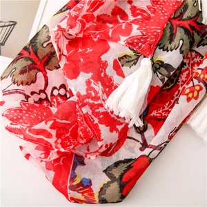 Detail of floral Bali yarn scarf with vibrant red flowers and white cotton tassels