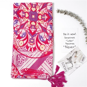 Close-up of bohemian pink floral print shawl with decorative fringe tassels on edges