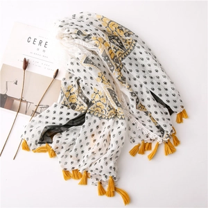 Close-up of cotton linen scarf featuring lace edges and vibrant yellow tassel details