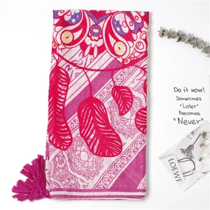 Detail of rose red bohemian beach scarf with tassel trim and ethnic feather patterns