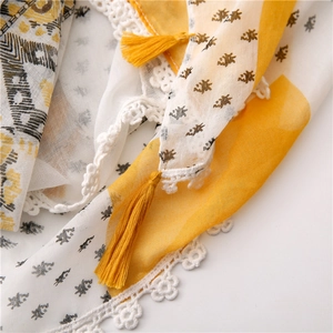Close-up of floral cotton linen scarf featuring white lace edges and yellow tassels