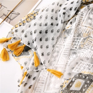 Detail of lace stitching and yellow tassels on cotton linen scarf with geometric pattern