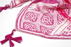 Close-up of rose red and white ethnic scarf detail with tassel edges and geometric patterns