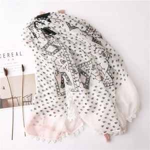 Detail of bohemian lace trim and pink tassels on a lightweight cotton linen scarf
