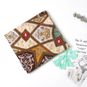 Detail of colorful geometric print silk scarf featuring vibrant mint green fringe tassels