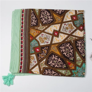Detail of bohemian silk scarf with geometric patterns and fringe tassels on white background