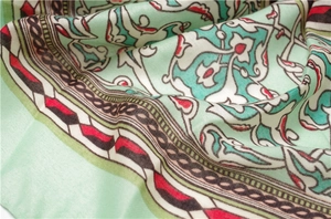 Detailed close-up of mint green silk scarf with ethnic geometric paisley print and soft texture
