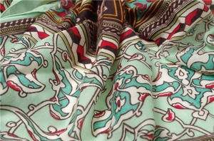 Detail of bohemian silk scarf with geometric floral pattern in mint green and red
