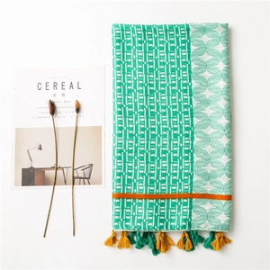 Détail de l'écharpe en lin bicolore vert et blanc avec pompons jaunes et motifs géométriques