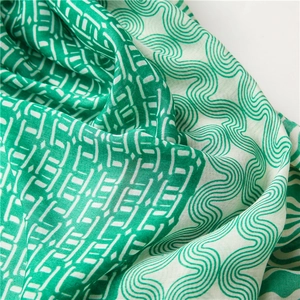 Détail du motif à vagues géométriques vert et blanc sur une écharpe en coton et lin