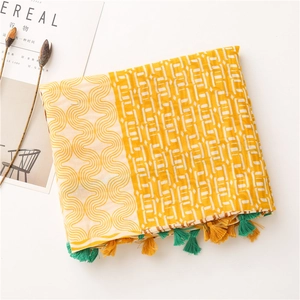 Détail d'une écharpe jaune et blanche avec motifs ondulés et bords à pompons
