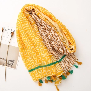 Détail de l'écharpe en coton lin à rayures jaunes et blanches avec pompons et texture douce