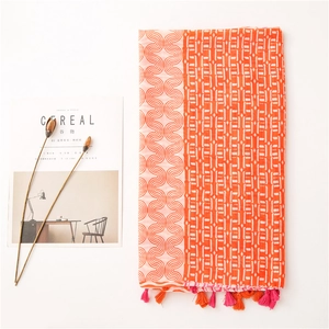 Détail de l'écharpe en coton et lin orange et rose avec pompons et motifs géométriques