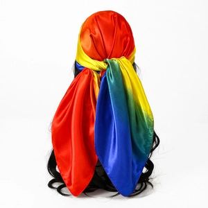 Dettaglio di un foulard in raso sfumato arcobaleno legato ai capelli con finitura setosa