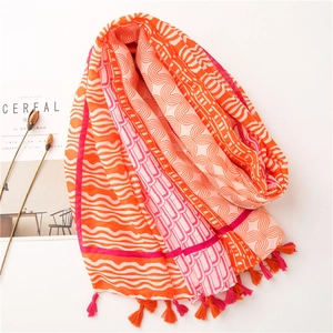 Détail d'une écharpe bohème aux motifs géométriques orange et rose avec des franges