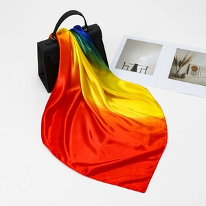 Foulard di raso con sfumatura arcobaleno annodato come decorazione su una borsa nera