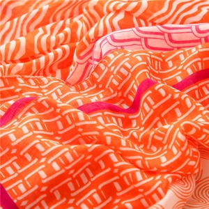 Détail macro d'une écharpe en coton et lin aux motifs géométriques orange et rose vif