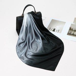 Elegante sciarpa in seta sfumata bianca e nera drappeggiata su una borsa classica
