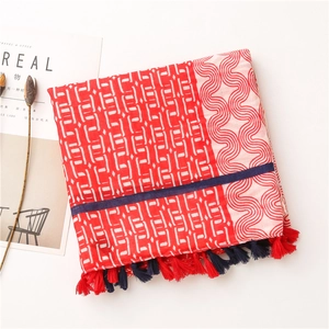 Détail d'écharpe en coton et lin à motif géométrique rouge et blanc avec pompons bicolores