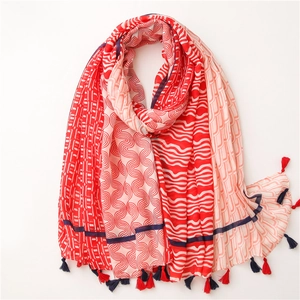 Détail d'une écharpe en coton et lin rouge et crème avec motifs géométriques et franges