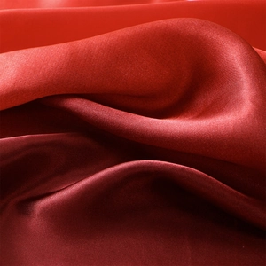 Dettaglio del tessuto di raso rosso con trama lucida e pieghe setose ed eleganti