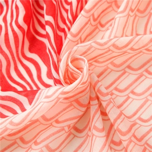 Détail d'une écharpe légère rouge et blanche montrant des motifs ondulés et la texture