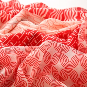 Gros plan sur la texture d'une écharpe en coton et lin avec motif patchwork rouge et rose