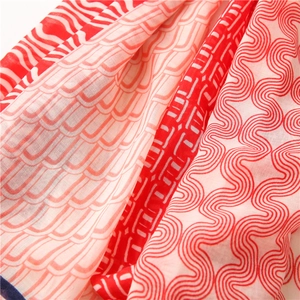 Vue détaillée d'une écharpe en coton et lin montrant des motifs géométriques rouges et blancs