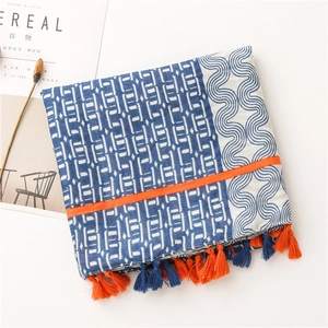 Détail d'écharpe bohème montrant des motifs bleus, ruban orange et glands faits main