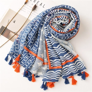 Détail d'une écharpe en lin color-block avec motifs géométriques et pompons orange