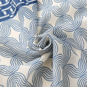 Détail d'une écharpe légère bleue et blanche avec motifs à vagues et texture douce